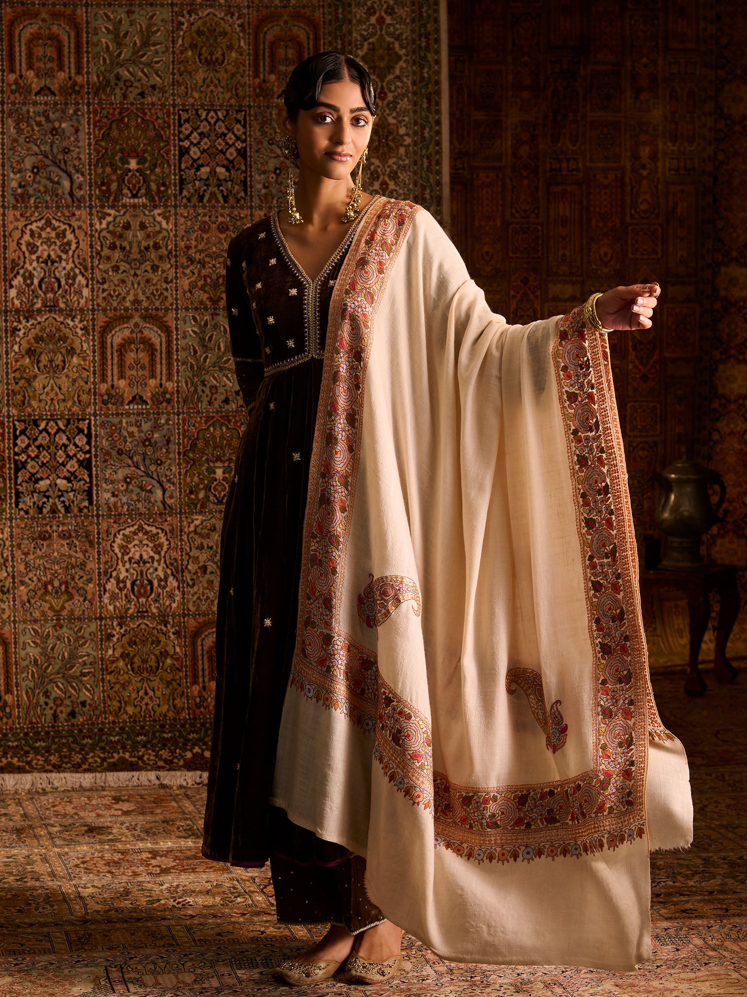 Woman in traditional attire with a white pashmina shawl in a decorated room